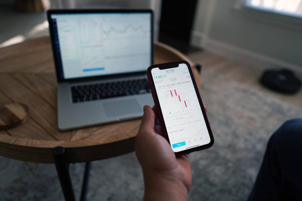 Trader analyzing forex market liquidity and price action charts on a mobile trading app and laptop.