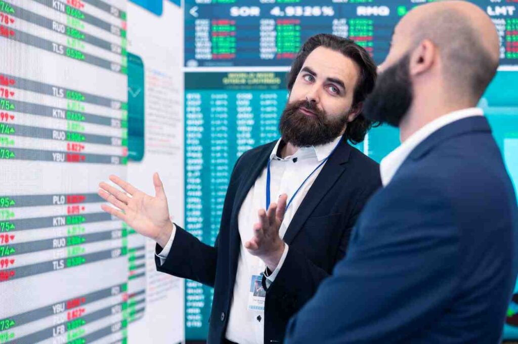Professional traders analyzing financial market data and discussing disciplined trading strategies on a live trading floor.