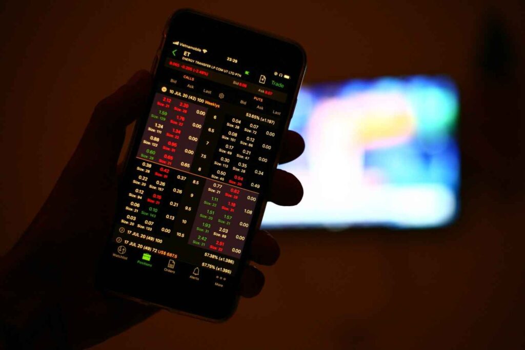 Trader monitoring market data on a mobile trading app, highlighting the importance of patience, discipline, and knowing when to stay out of the market during uncertain conditions.