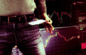 Trader showing empty pockets in front of trading charts representing trading losses and poor risk management.
