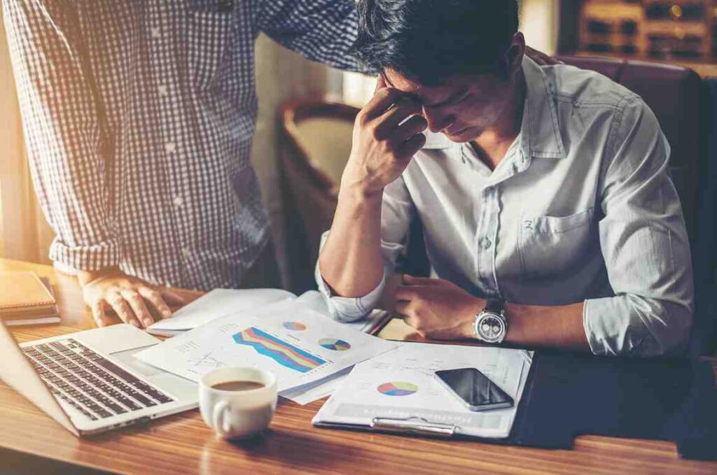 Trader looking frustrated and disengaged while reviewing market charts and trading reports, illustrating how boredom can lead to poor decisions, overtrading, and emotional mistakes in trading.