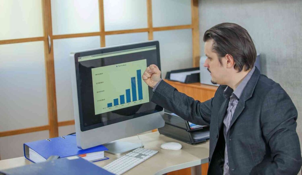 Trader closely watching a rising performance chart on a computer screen, illustrating the impatience and unrealistic expectations many traders develop when seeking quick results from a trading strategy.