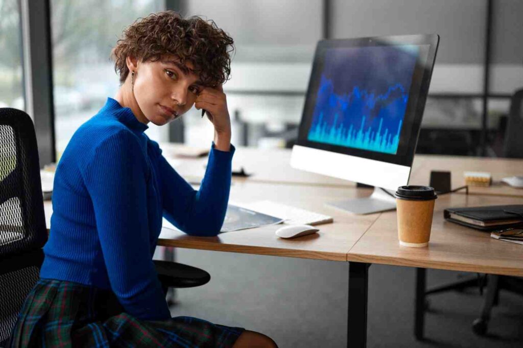 Trader sitting thoughtfully in front of market charts after a losing trade, illustrating how ego can make it difficult to accept losses and remain objective in trading.