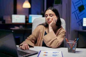 Trader sitting in front of market charts with a bored expression, illustrating how disciplined trading often involves patience, waiting for high-quality setups, and avoiding unnecessary market activity.