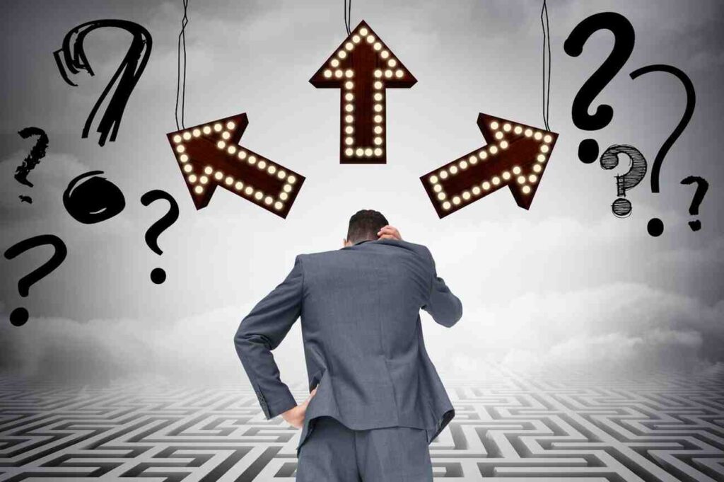Businessman standing at a crossroads with directional arrows and question marks, representing how recency bias affects trading decisions and influences trader psychology.
