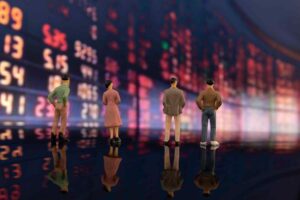 Miniature investors standing in front of a stock market display, illustrating how recency bias influences trading decisions, market sentiment, and investor behavior based on recent price movements.