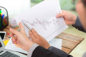 Trader reviewing a financial market chart on paper, illustrating how recency bias can hurt trading performance by influencing decisions based on recent price movements rather than long-term analysis.