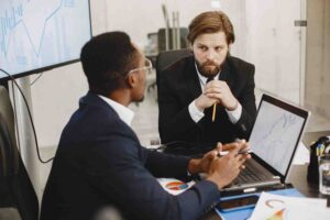 Professional traders reviewing financial charts during a strategy discussion, illustrating how disciplined analysis and long-term planning help avoid recency bias in trading decisions.